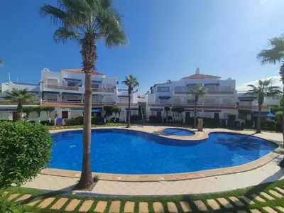 a large blue swimming pool with palm trees in front of buildings at Passadena Village, Sidi Rahal in Sidi Rahal