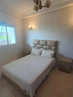 a bedroom with a large bed with white sheets and a window at Passadena Village, Sidi Rahal in Sidi Rahal