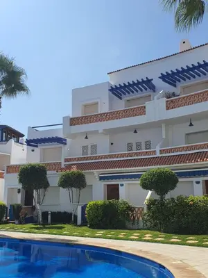 a building with a swimming pool in front of it at Passadena Village, Sidi Rahal in Sidi Rahal