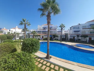a swimming pool with a palm tree and buildings at Passadena Village, Sidi Rahal in Sidi Rahal
