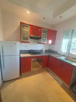 a kitchen with red cabinets and a white refrigerator at Passadena Village, Sidi Rahal in Sidi Rahal