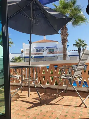 a table and chair with an umbrella and palm trees at Passadena Village, Sidi Rahal in Sidi Rahal