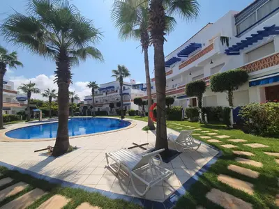 a swimming pool with palm trees in front of a building at Passadena Village, Sidi Rahal in Sidi Rahal