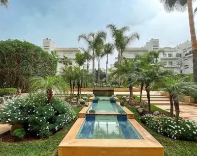 a swimming pool in a garden with palm trees at Luxueux appartement Bay view dans une résidence avec magnifique jardin in Casablanca