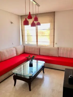 a living room with a red couch and a window at Luxueux appartement Bay view dans une résidence avec magnifique jardin in Casablanca