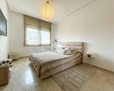 a bedroom with a large bed and a chandelier at Luxueux appartement Bay view dans une résidence avec magnifique jardin in Casablanca