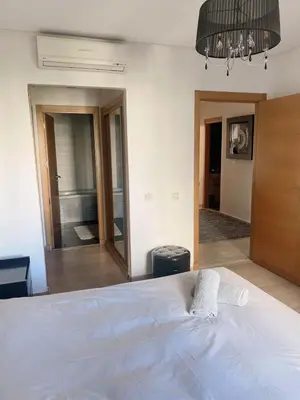 a bedroom with a white bed and a large mirror at Luxueux appartement Bay view dans une résidence avec magnifique jardin in Casablanca