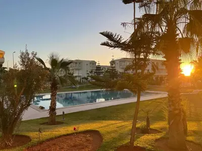 a view of a pool with palm trees and buildings at Superbe Appartement Bord de mer in Bouznika