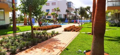 a walkway in a park next to a building at Bleu Beach uniquement pour famille in Sidi Rahal