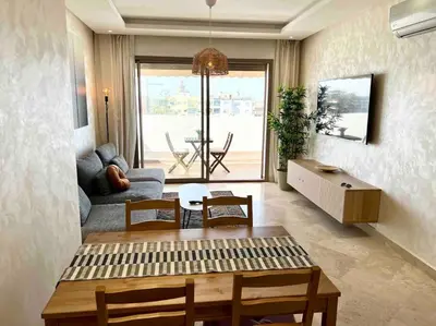 a living room with a table and a couch at DreamParc - Vue sur Mer et Parc Securite 24H in Mohammedia