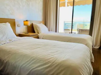 two beds in a hotel room with a window at DreamParc - Vue sur Mer et Parc Securite 24H in Mohammedia
