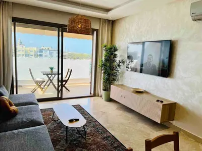 a living room with a couch and a tv at DreamParc - Vue sur Mer et Parc Securite 24H in Mohammedia