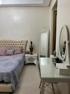 a bedroom with a bed and a table and a mirror at Maison Bleu in Mansouria