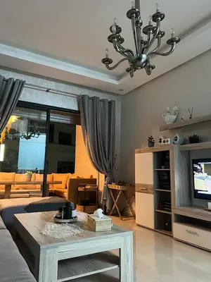 a living room with a couch and a table and a television at Maison Bleu in Mansouria
