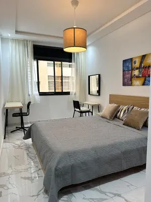 a bedroom with a large bed and a table at Appartement BMK N-1 in Rabat