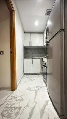 a kitchen with white cabinets and a stainless steel refrigerator at Appartement BMK N-1 in Rabat
