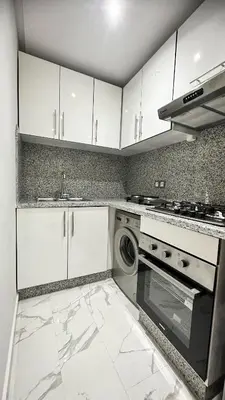 a kitchen with white cabinets and a washer and dryer at Appartement BMK N-1 in Rabat
