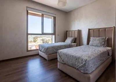 a bedroom with two beds and a window at Modern Charm at Le Joyau du Parc in Mohammedia
