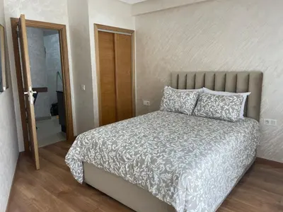 a bedroom with a large bed and a bathroom at Studio meublé neuf à louer in Casablanca