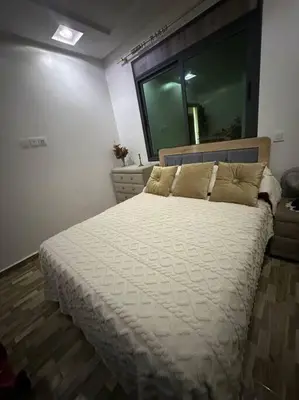 a bedroom with a large bed with white sheets and a mirror at Appartement vue sur mer sidi Rahal in Sidi Rahal