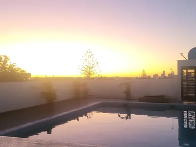 a swimming pool with the sunset in the background at Chez Joe - Location journalière Casablanca in Casablanca