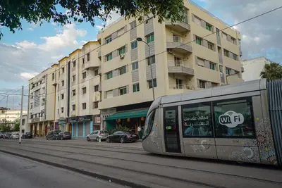 a bus driving down a street in front of a building at New Appartment in Rabat