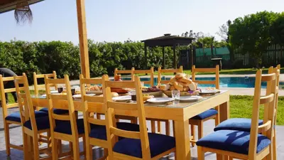a wooden table with chairs and a table with food on it at Maison de Campagne in Dar SaÃ¯d Ben Hajj