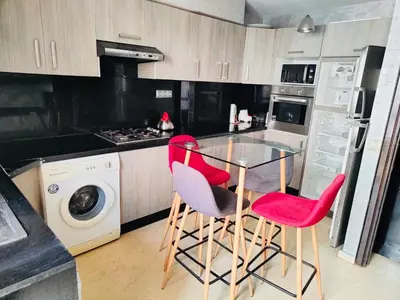 a kitchen with a glass table and two red chairs at Luxury apartments 3 in Casablanca