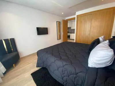 a bedroom with a large bed and a television at Corniche Casablanca - Black New in Casablanca