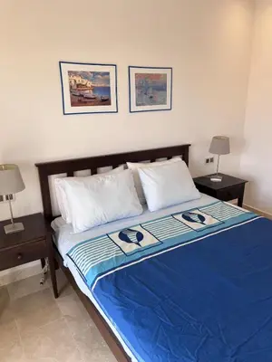 a bedroom with a bed with blue sheets and two night stands at North Beach Plage & Confort in Mansouria