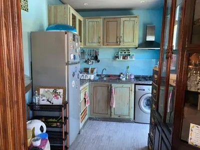 a kitchen with wooden cabinets and a white refrigerator at Maison du bonheur in El Harhoura