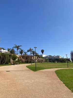 a park with palm trees and a sidewalk at Maison du bonheur in El Harhoura