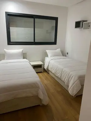 two beds in a room with a window at Prestigia Appartement Luxueux in Rabat