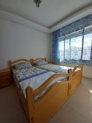 a bedroom with a wooden bed and a window at Bel Appartement à Mansbay in Mansouria