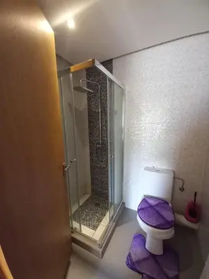 a bathroom with a shower and a toilet with purple mats at Bel Appartement à Mansbay in Mansouria