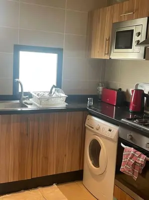 a kitchen with a washing machine and a microwave at Nice appartement pool & sea view in Dar Bouazza