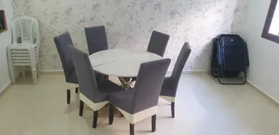 a dining room with a table and chairs and a suitcase at Ilyass Garden Beach Sidi Rahal in Dar Hamida
