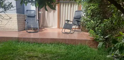 two chairs sitting on a patio next to a building at Ilyass Garden Beach Sidi Rahal in Dar Hamida