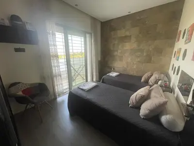 a bedroom with two beds and a stone wall at BEAU TRIPLEX EN RESIDENCE in Skhirat