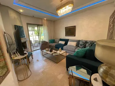 a living room with a couch and a tv at BEAU TRIPLEX EN RESIDENCE in Skhirat