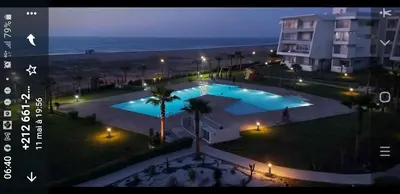 a view of a swimming pool at night with the beach at Luxueux appartement front mer in Sidi Rahal