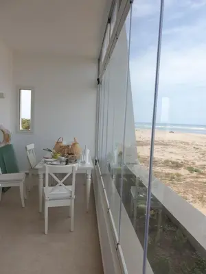 a dining room with a table and a view of the beach at Luxueux appartement front mer in Sidi Rahal