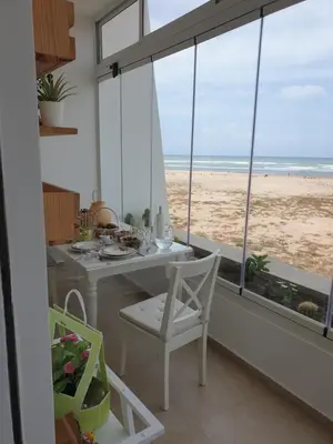 a dining room with a table and a view of the beach at Luxueux appartement front mer in Sidi Rahal