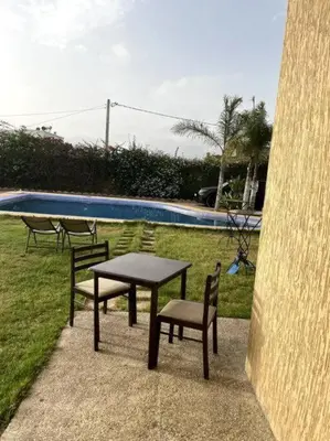 a table and chairs next to a swimming pool at Villa avec piscine et jardin privés in Casablanca