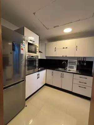 a kitchen with white cabinets and a stainless steel refrigerator at Appartement meublé piscine Residence eden tamaris in Dar Bouazza