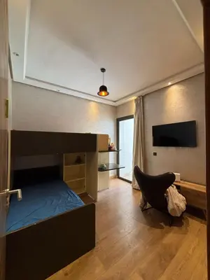 a bedroom with a bed and a chair and a television at Appartement meublé piscine Residence eden tamaris in Dar Bouazza