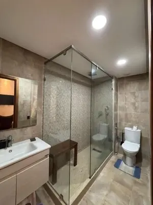 a bathroom with a shower and a toilet and a sink at Appartement meublé piscine Residence eden tamaris in Dar Bouazza