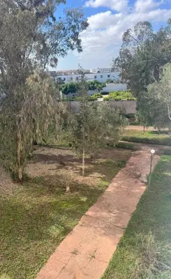 a path in a park with trees and a river at Casablanca Beautiful and Tranquil Family Apartment in Casablanca