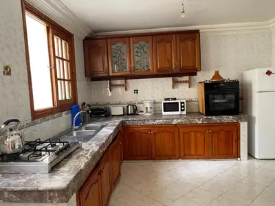 a kitchen with wooden cabinets and a white refrigerator at Rez-de-jardin à Mohammedia in Mohammedia