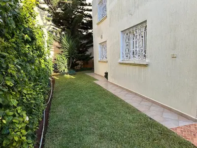 a cat sitting on the grass next to a building at Rez-de-jardin à Mohammedia in Mohammedia